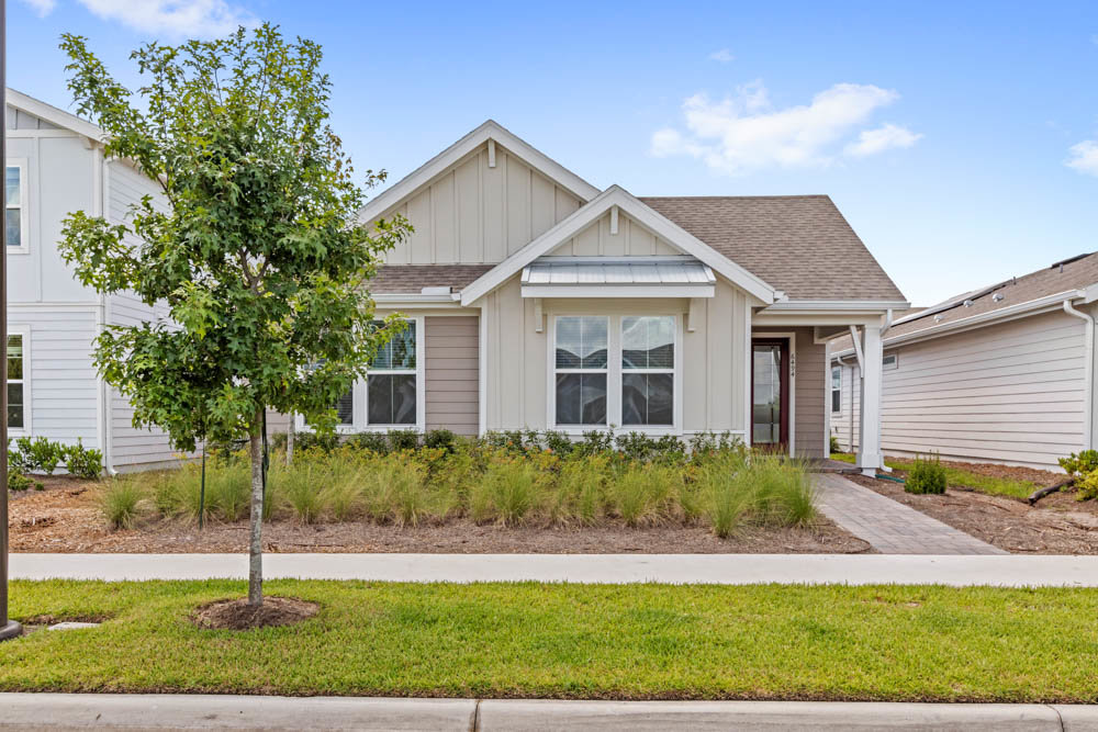 front of one story home with beige paint and small tree